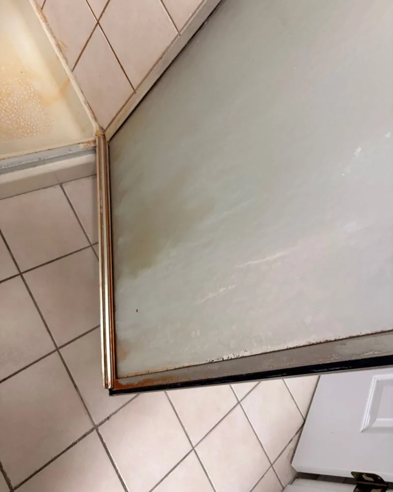 Close-up of soap scum on the shower door glass before cleaning