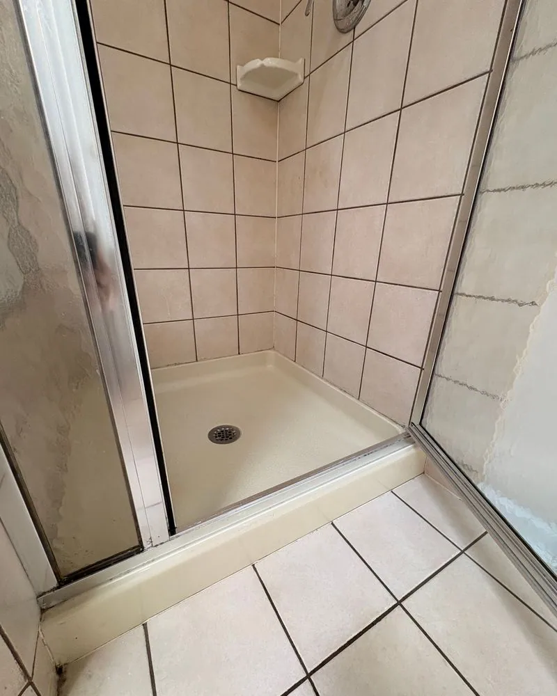 The same shower pan after cleaning, bright white with clean tile