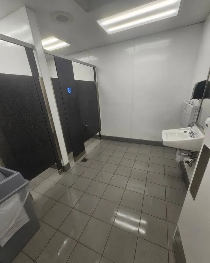 Commercial restroom with stalls and a tiled floor after cleaning
