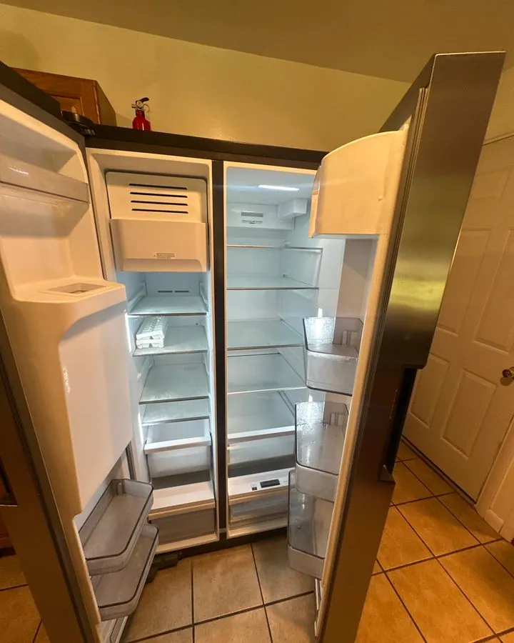 Empty side-by-side refrigerator with clean shelves and drawers